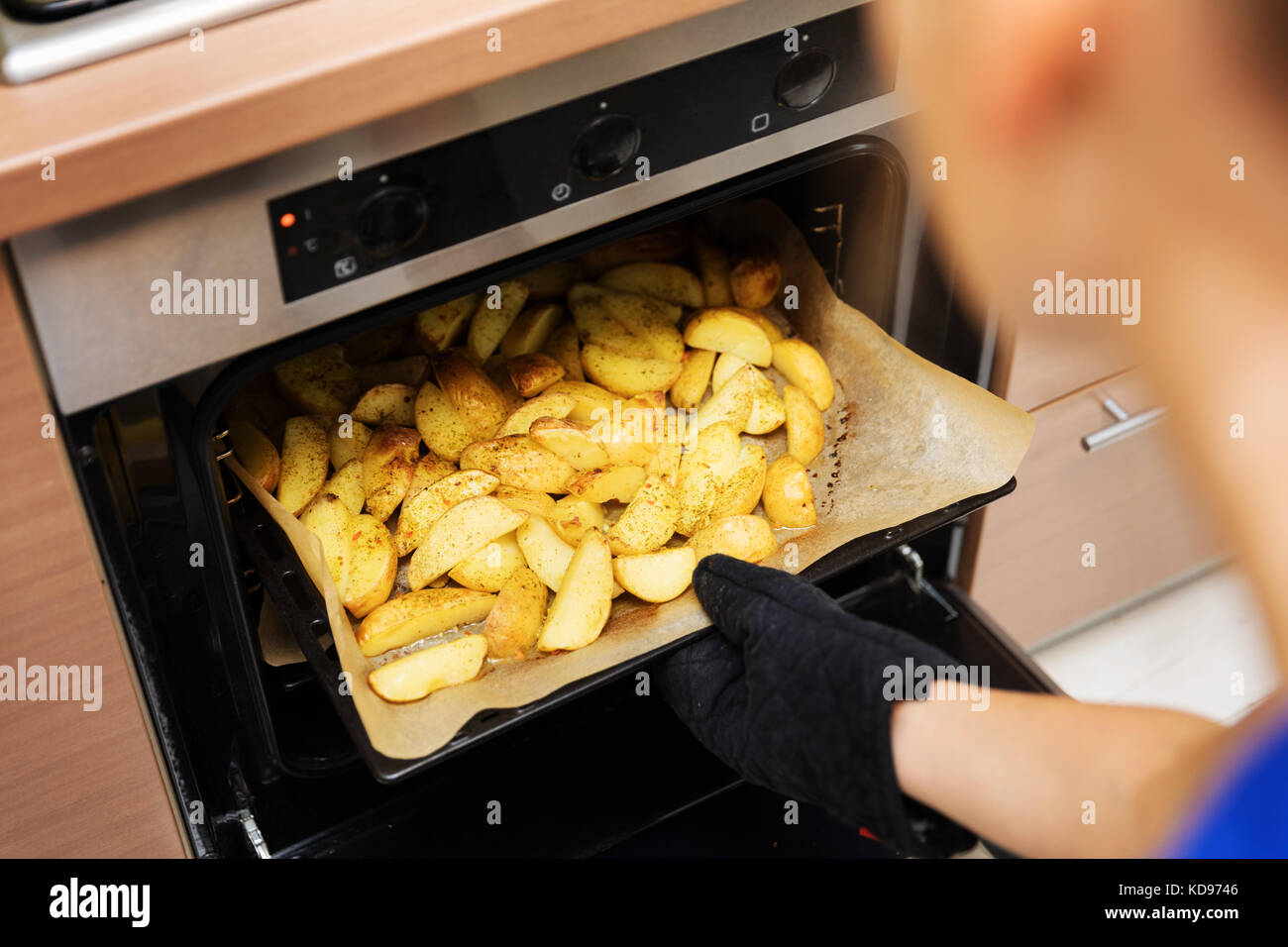 Donna rimozione preparati Patate vassoio fuori del forno Foto Stock