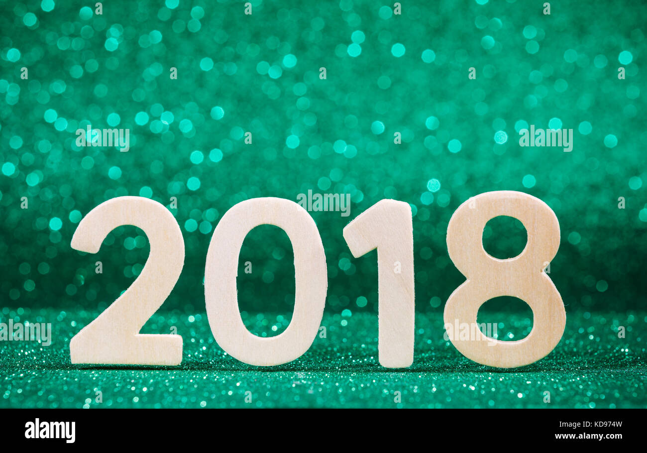 Nuovo anno 2018 bianco numero di legno su carta verde glitter con luci Foto Stock