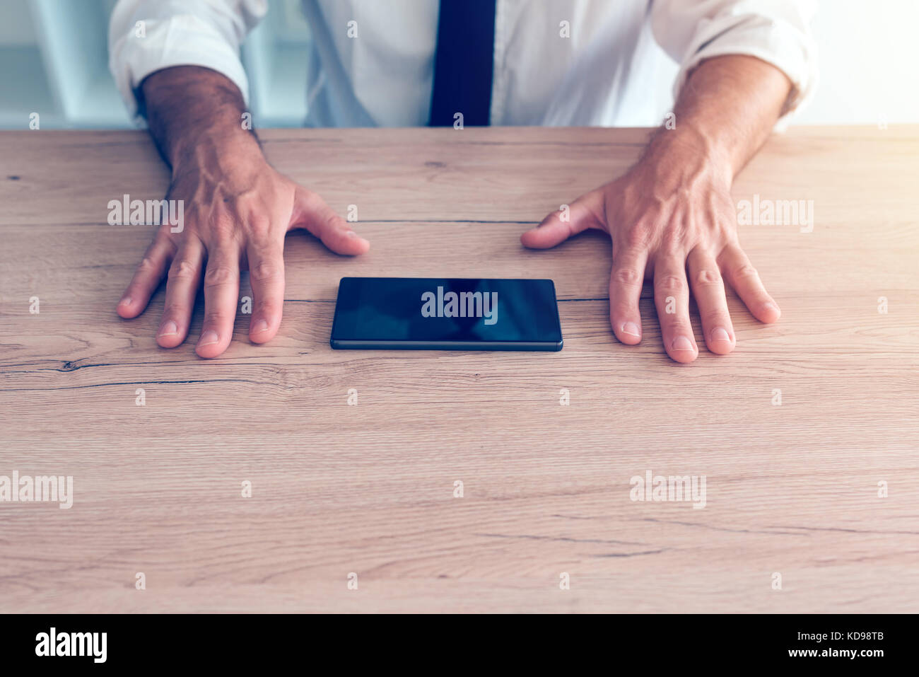 Imprenditore lotta telefono cellulare dipendenza crisi. persona d'affari facendo sforzi per resistere allo smartphone utilizzando il dispositivo sulla scrivania in ufficio. Foto Stock