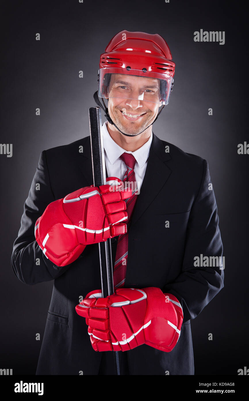 Ritratto di un imprenditore maturo vestito come giocatore di hockey su sfondo nero Foto Stock