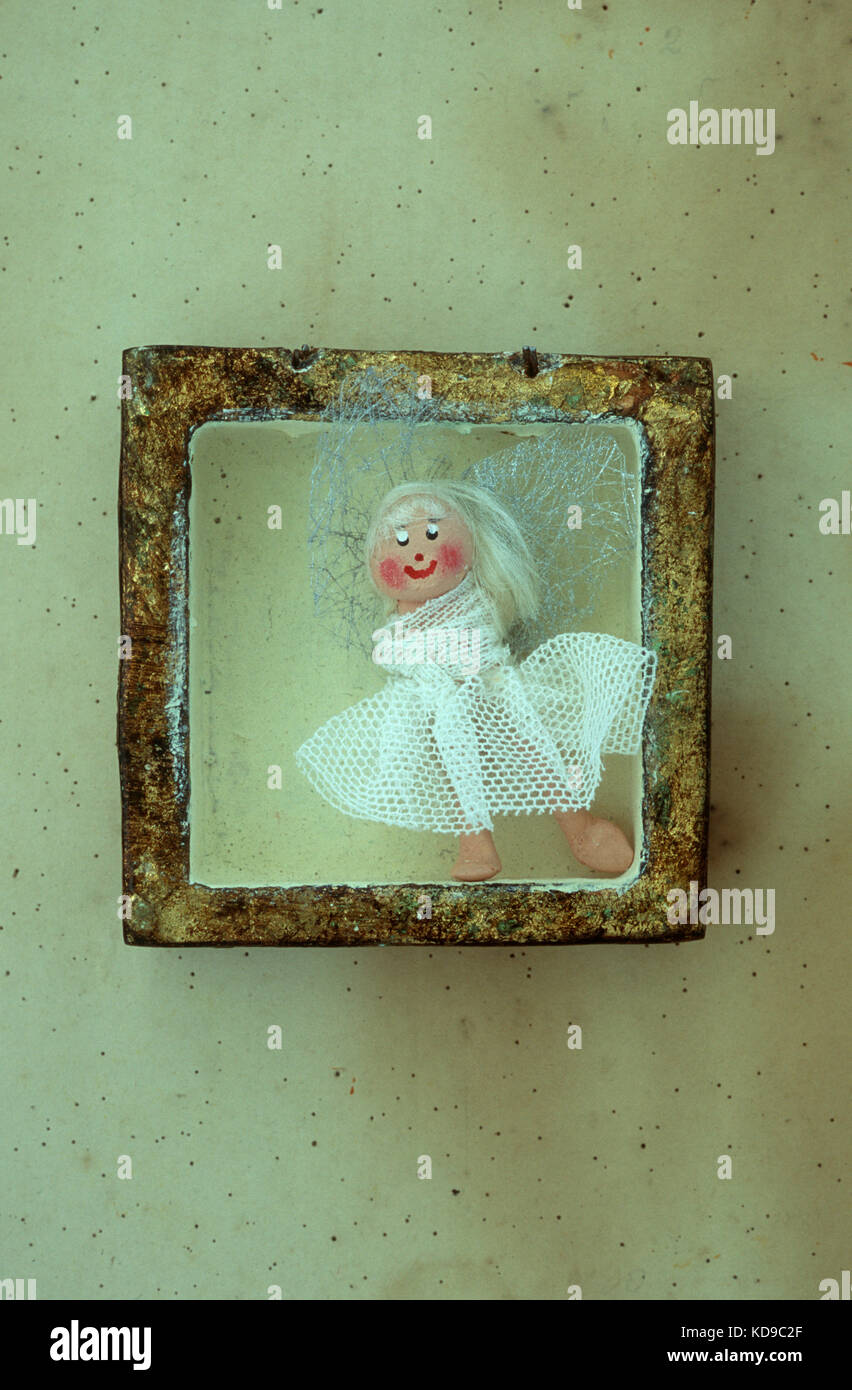 Carino divertente modello di angelo alato o fata in bianco abito di garza appoggiata da angolo di piccole gold box Foto Stock