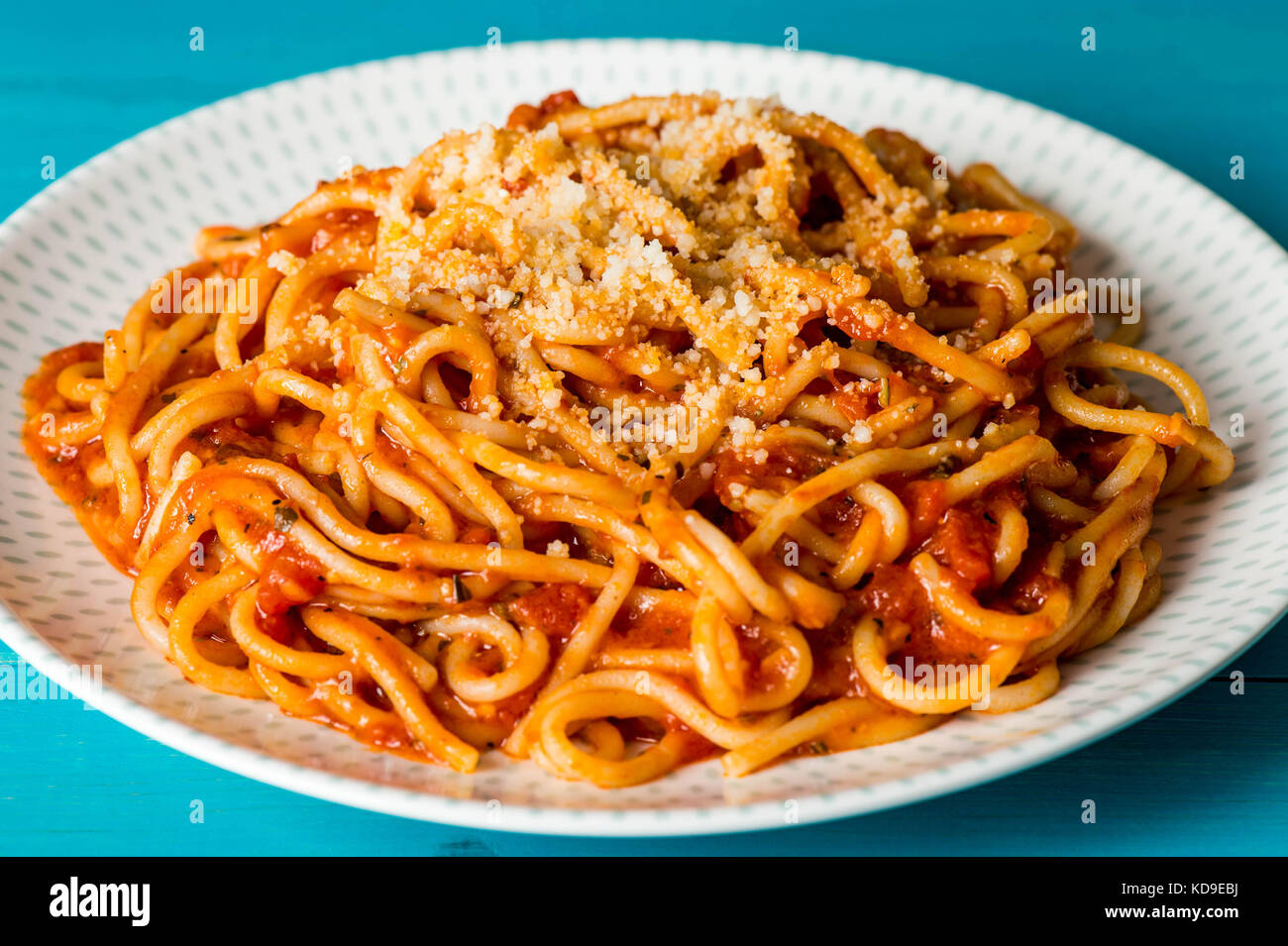 Piatto di spaghetti in salsa di pomodoro con parmeson grattugiate il formaggio su una tavola di legno sfondo blu Foto Stock