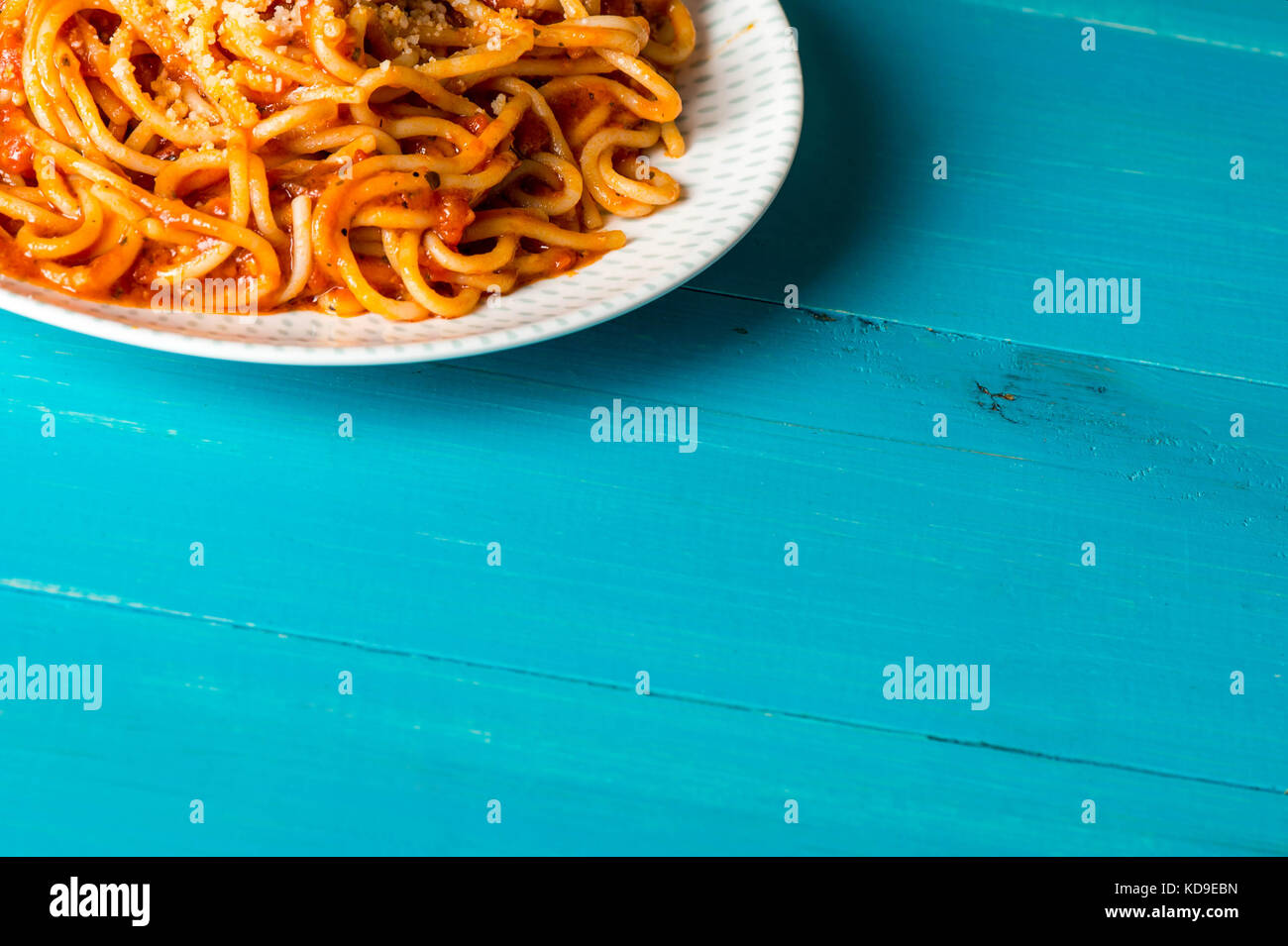 Piatto di spaghetti in salsa di pomodoro con parmeson grattugiate il formaggio su una tavola di legno sfondo blu Foto Stock