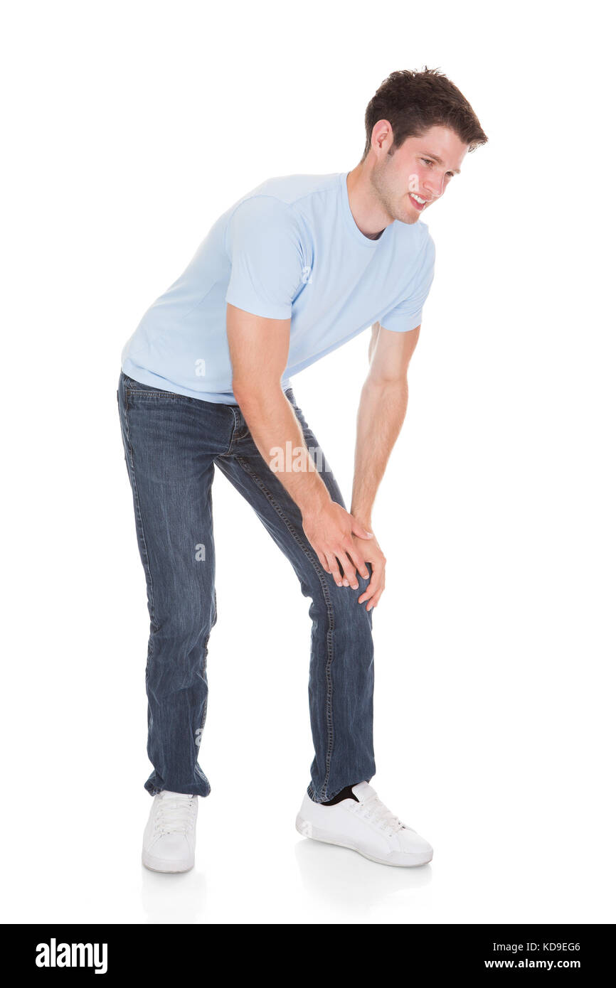 Giovane uomo che soffrono di dolore al ginocchio isolati su sfondo bianco Foto Stock