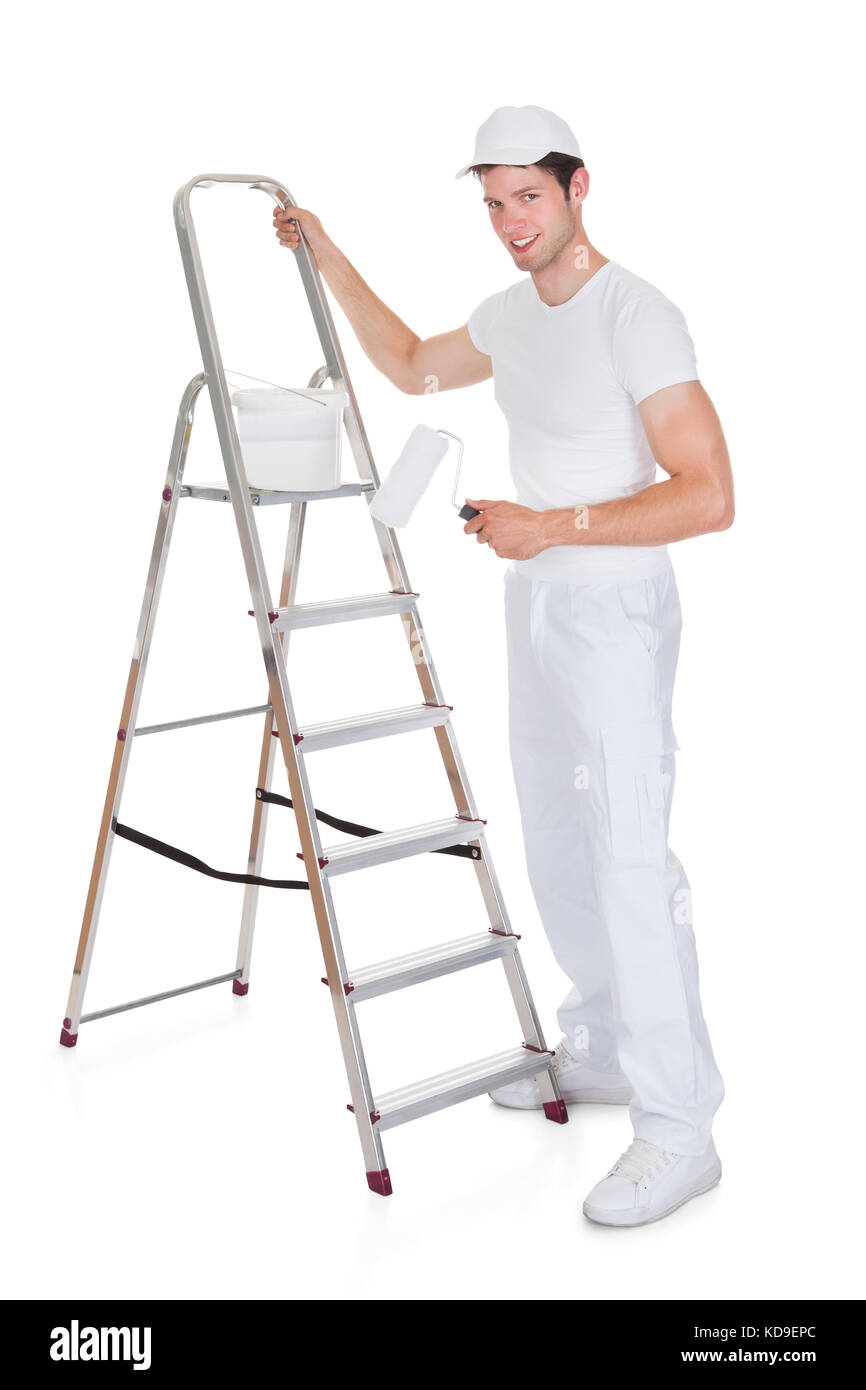 Felice pittore con secchio di vernice e il rullo in piedi sulla scaletta Foto Stock