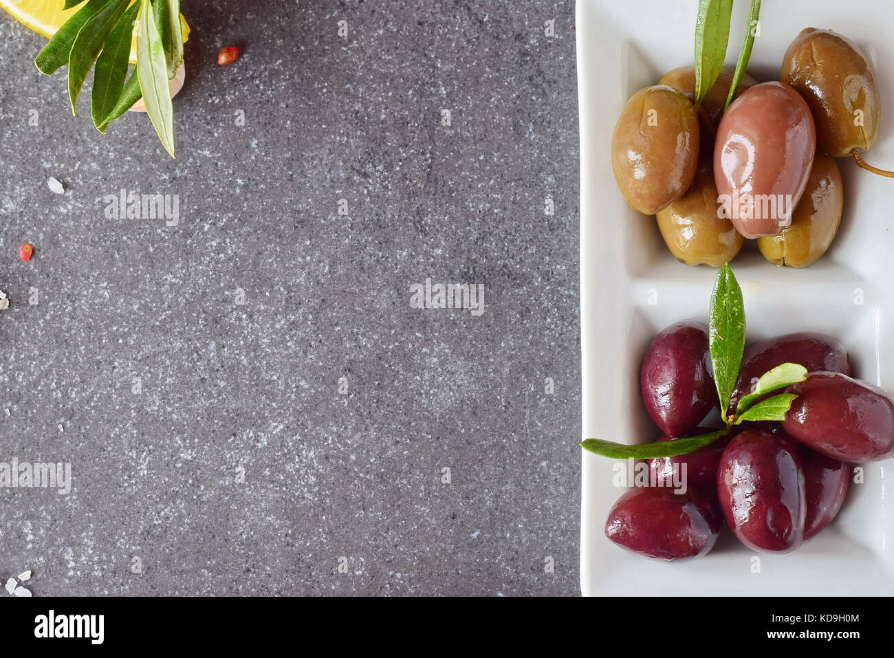 Piastra di olive nere e verdi su un grigio Sfondo astratto con la copia spazio. cibo sano concetto Foto Stock