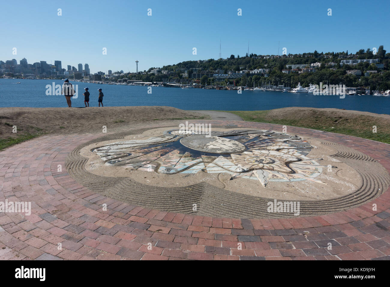 I turisti a scolpito analemmatic sundial in cima aquilone hill; Seattle skyline attraverso il lago union, lavori gas park, Seattle, Washington Foto Stock