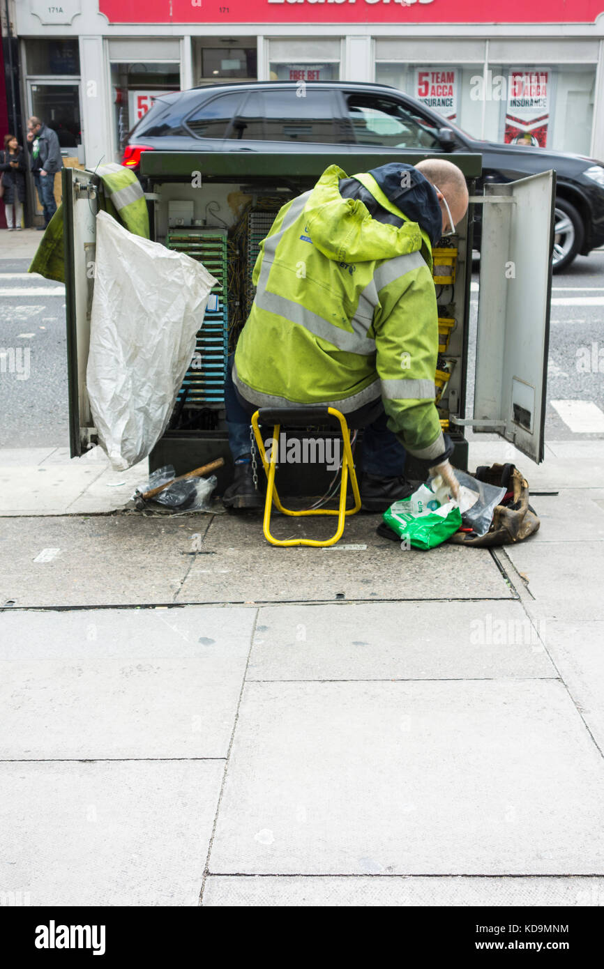 Un BT Openreach ingegnere delle telecomunicazioni installazione di filo di rame in un armadio di telecomunicazioni Foto Stock