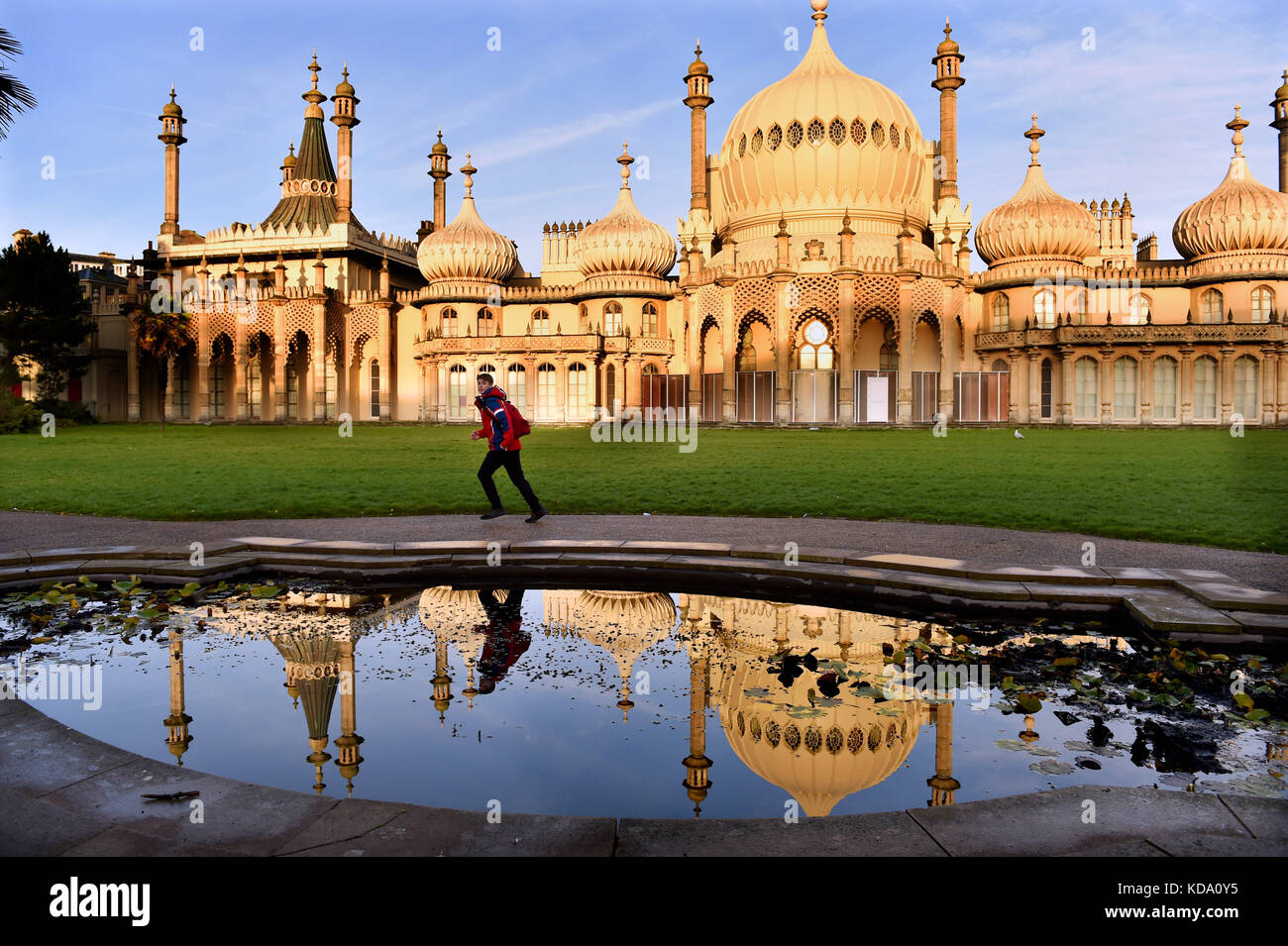 Brighton, Regno Unito. 12 ottobre 2017. Meteo nel Regno Unito. Un giovane passa accanto al Royal Pavilion di Brighton, che si riflette in uno degli stagni del giardino in una bella mattinata di sole con le previsioni meteo che saranno insolitamente calde nei prossimi giorni nel sud del Regno Unito Foto Stock