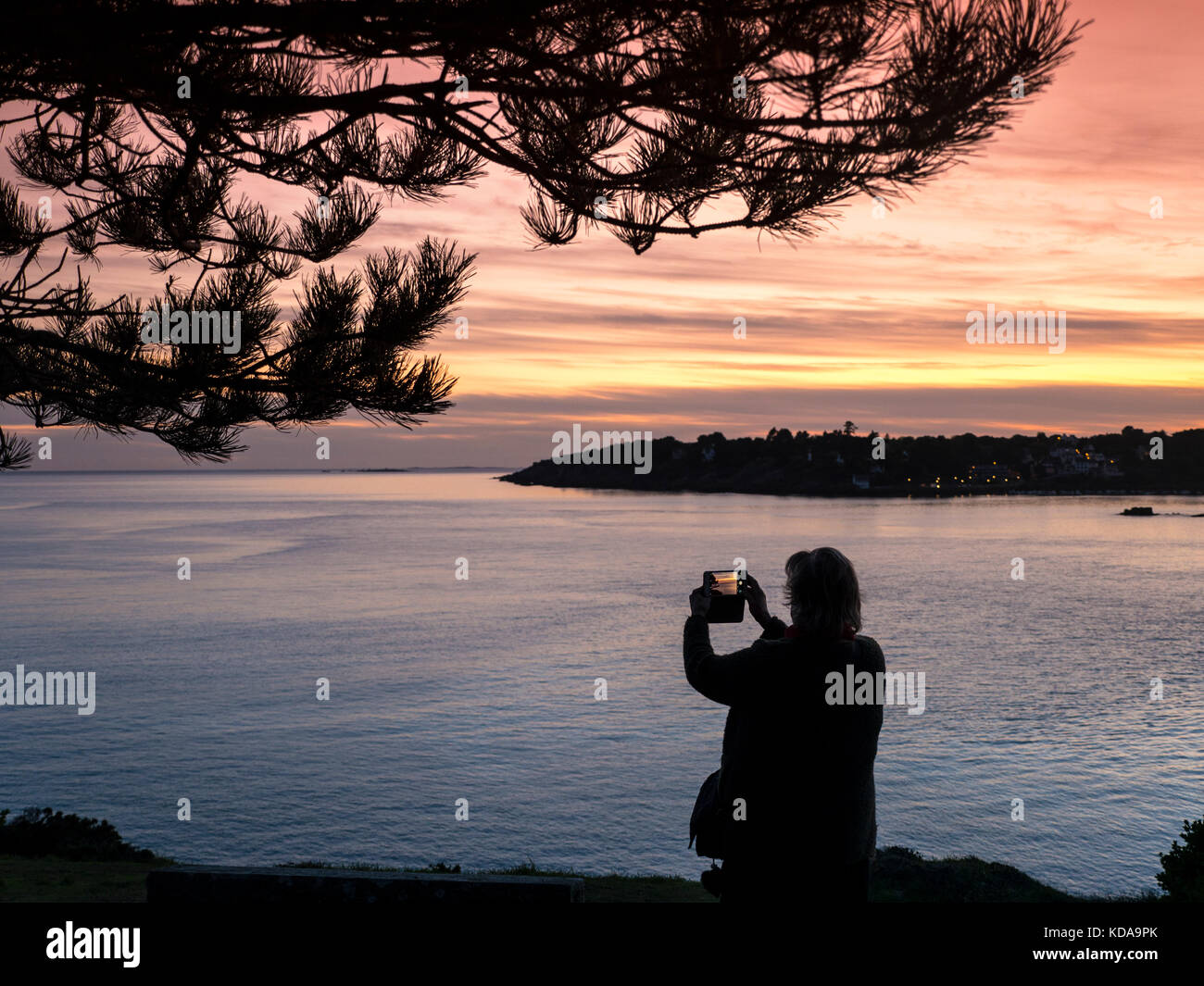 Paesaggio dello smartphone tramonto FOTO VIDEO KERFANY LES PINS donna prendendo un immagine di panorama di un tramonto costiera sul suo smartphone iPhone app Fotocamera Moëlan sur Mer Bretagna Francia Foto Stock