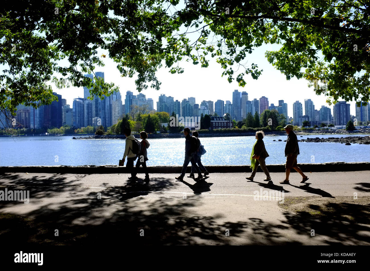 I turisti a piedi lungo un sentiero nel Parco di Stanley con la skyline di Vancouver n sullo sfondo. Foto Stock