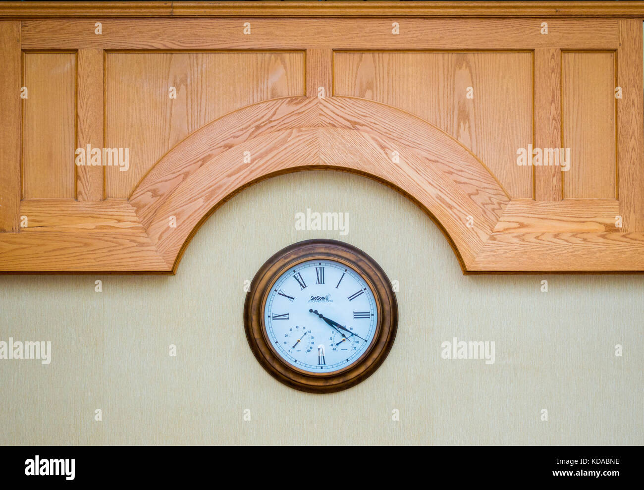 Classic orologio da parete con numeri romani sotto un scolpito sul pannello di legno Foto Stock