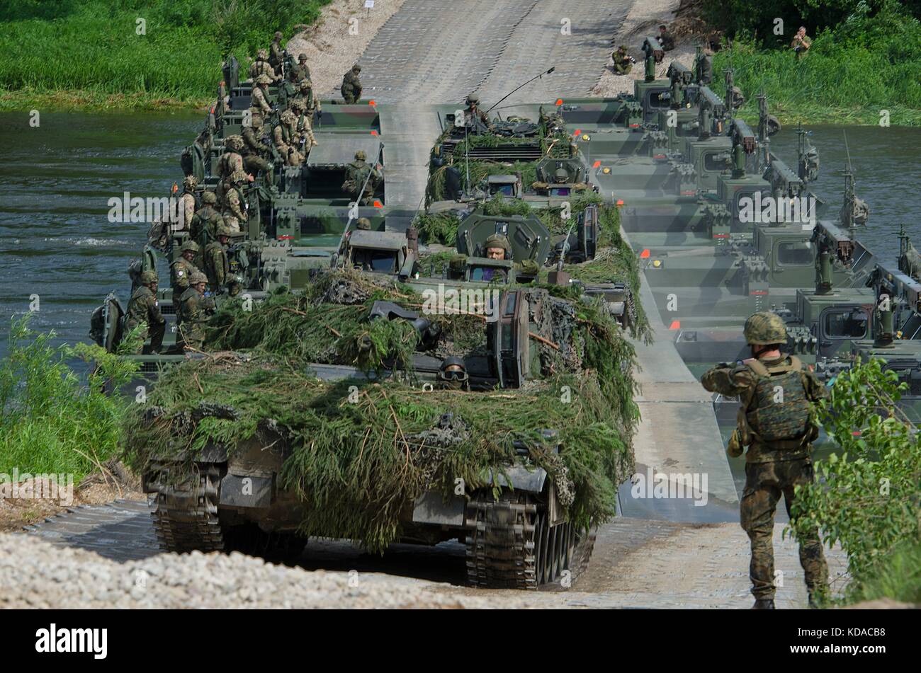 Soldati statunitensi, britannici, lituani e polacchi attraversano un ponte in un convoglio di veicoli da corsa durante l'esercitazione Saber Strike Iron Wolf, 20 giugno 2017 a Rukla, Lituania. Foto Stock