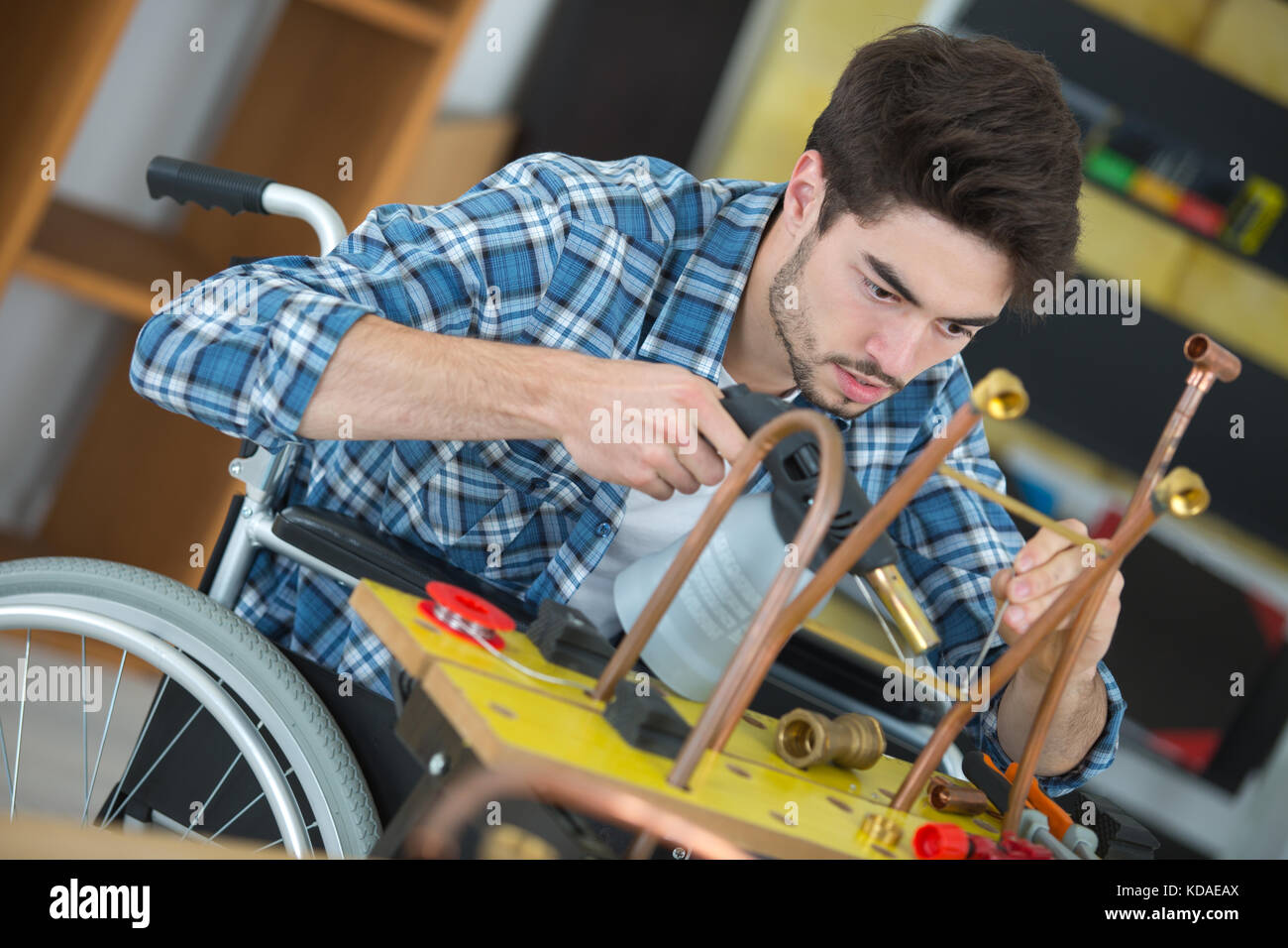 Lavoratore manuale in carrozzella lavora con tubi in metallo Foto Stock