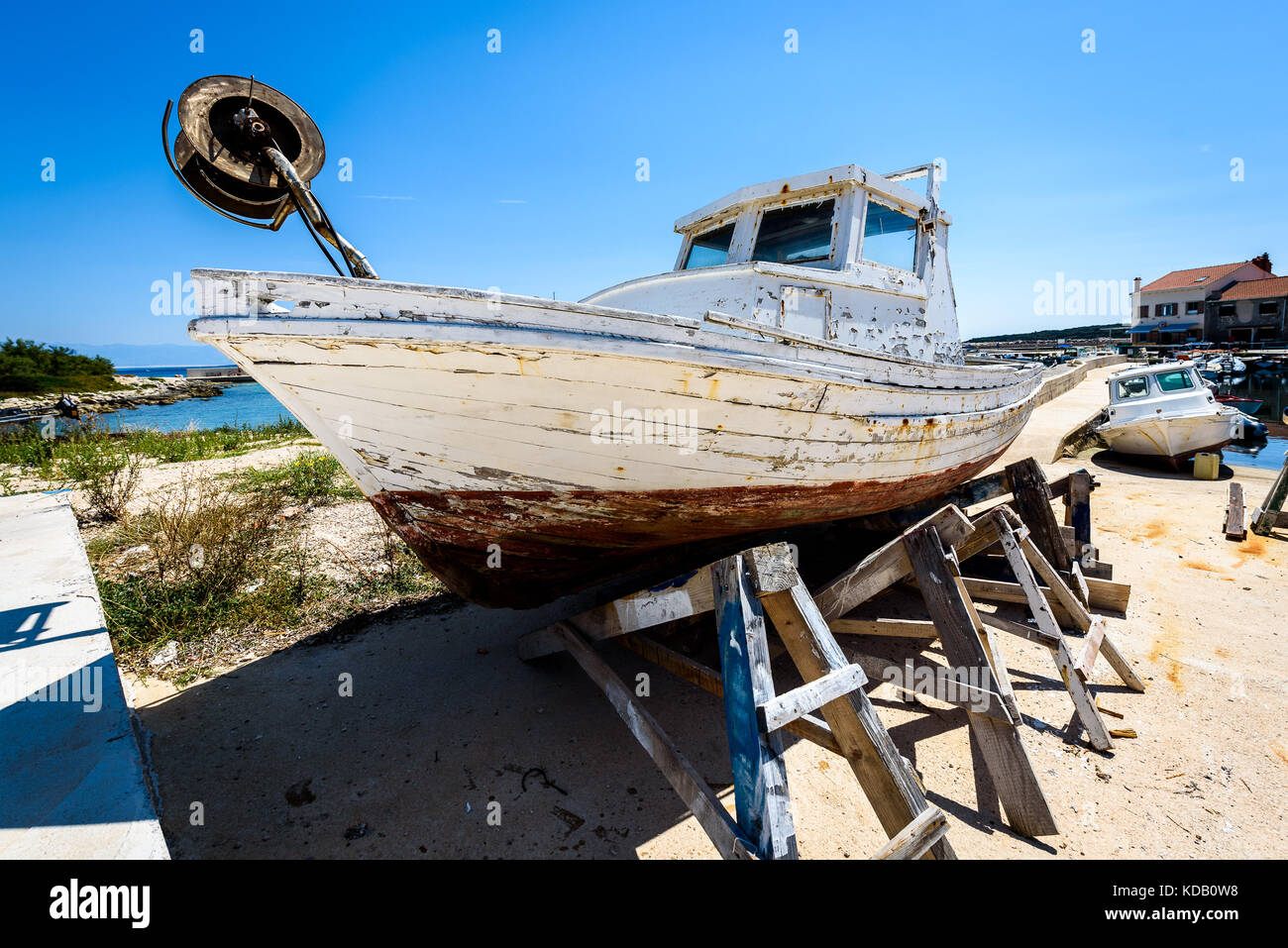 Riparazione e restauro di vecchi in legno nave da pesca o barca. vecchio weathered barca da pesca montata su martinetti in legno per il bacino di carenaggio riparazione e ristrutturazione con Foto Stock