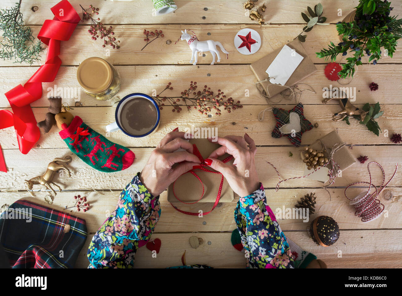 Donna decorazione di un regalo di Natale con un ramo di agrifoglio, fai-da-te decorazione di Natale Foto Stock