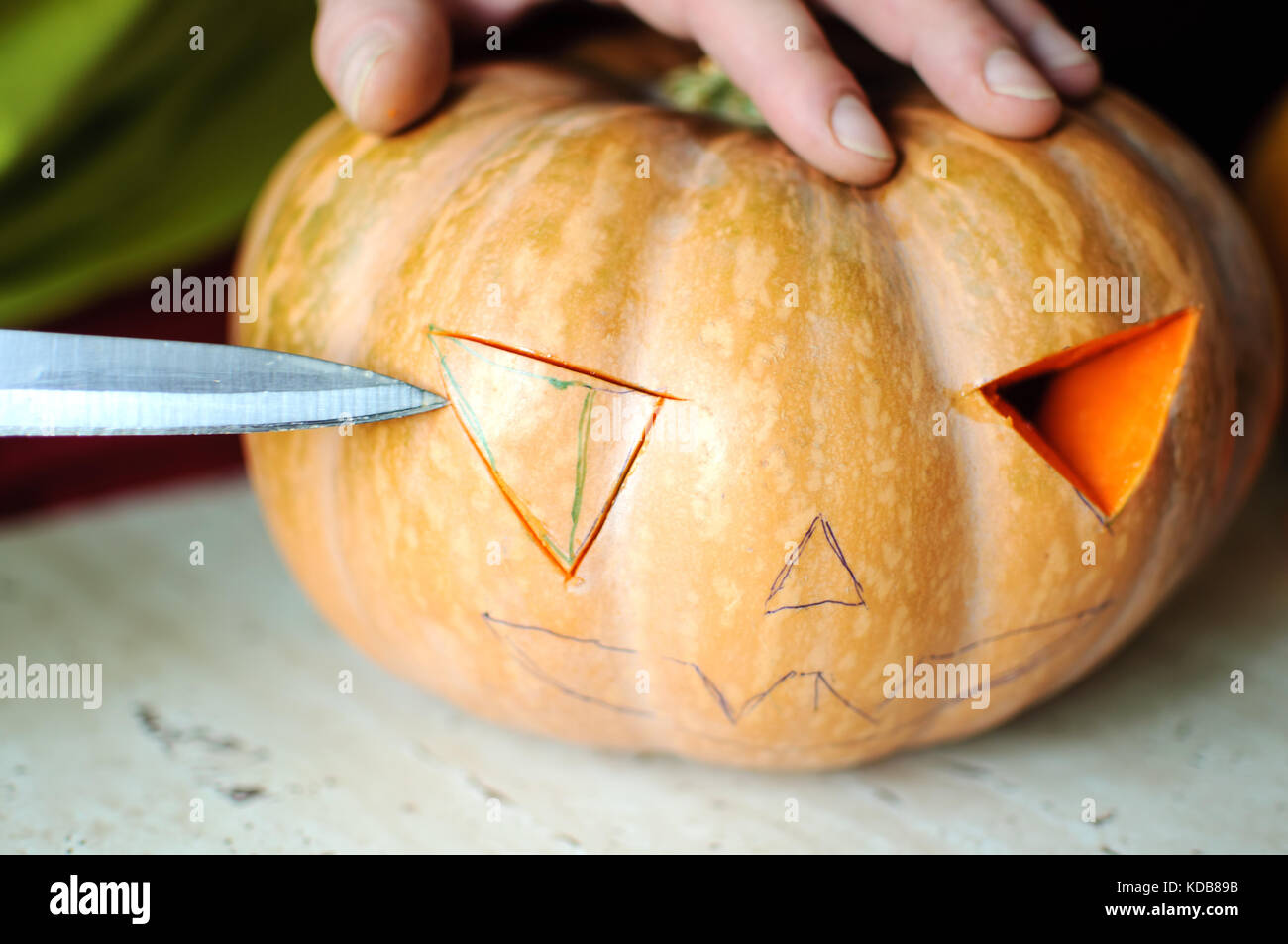 Zucca di Halloween processo di taglio, il processo di realizzazione di jack-o-lantern maschio mani con coltello, gli avanzi di zucca sul tavolo della cucina. messa a fuoco selettiva Foto Stock