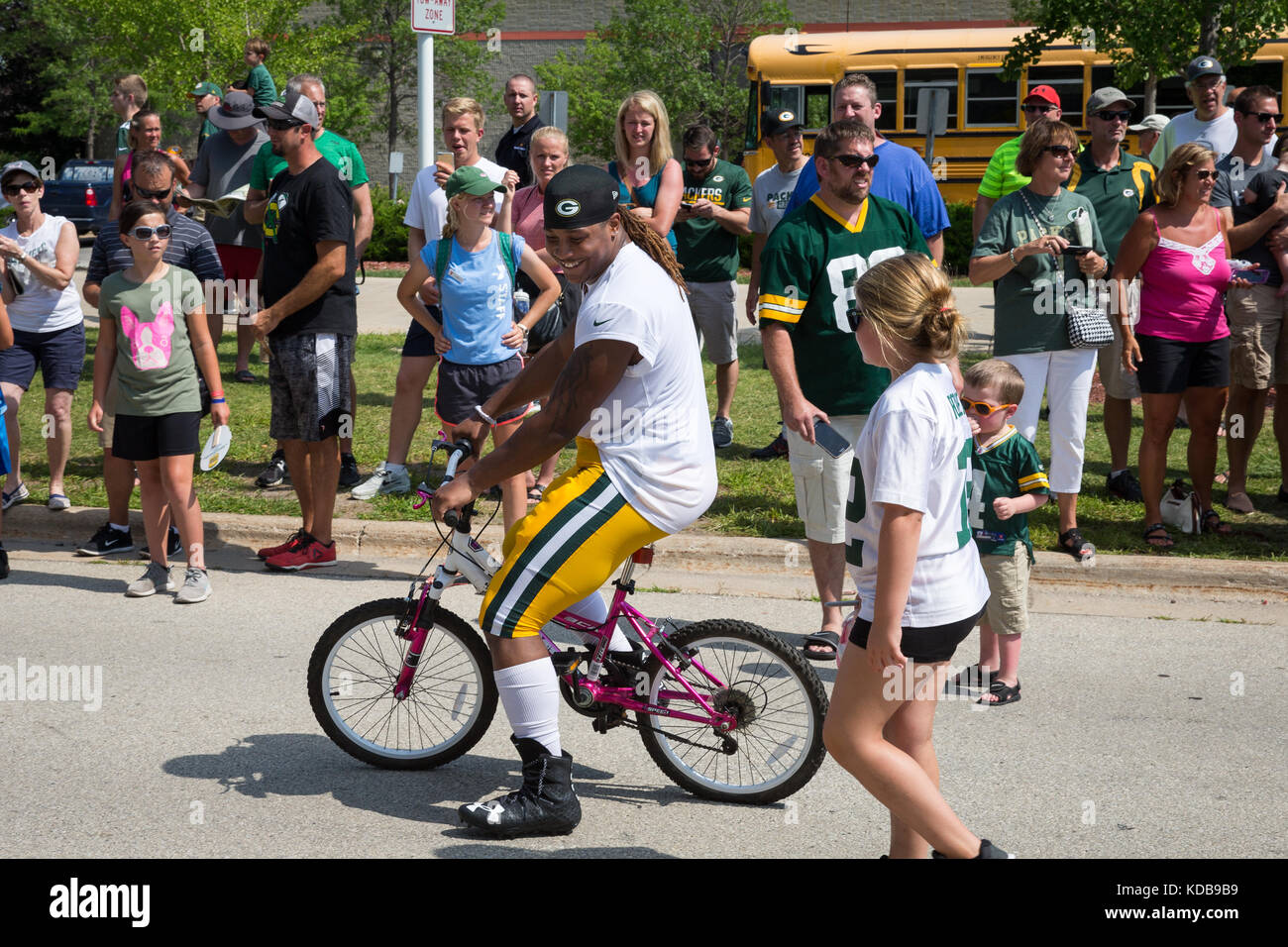 Green Bay, WI - 1 agosto 2017: green bay packer phillips kalif cavalca un giovane fan bike dopo la pratica di gioco del calcio. la comunità di proprietà team ha una lunga Foto Stock