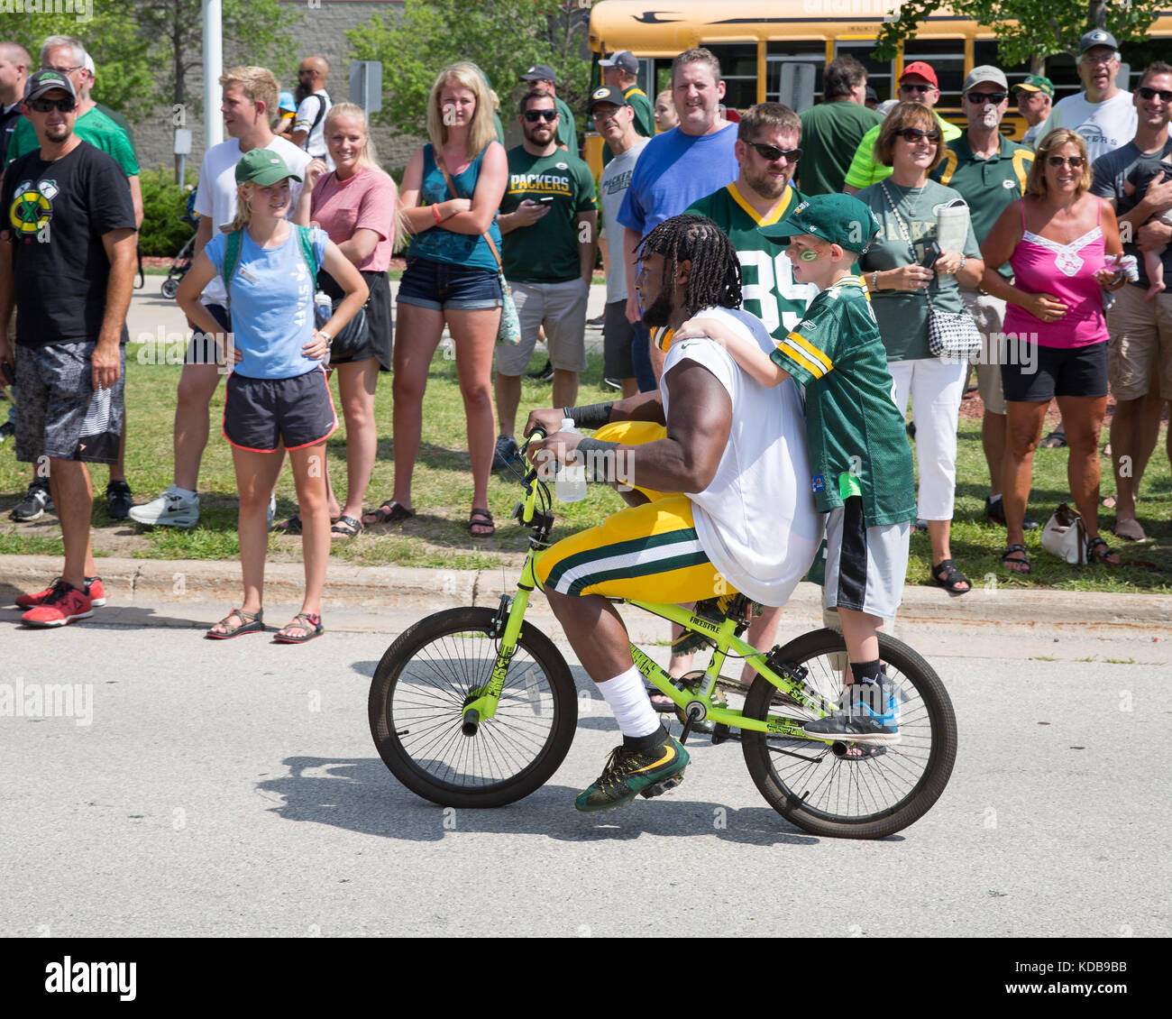 Green Bay, WI - 1 agosto 2017: Aaron Jones cavalca un giovane fan bike dopo la pratica di gioco del calcio. la comunità di proprietà Green Bay Packers hanno una lunga tradi Foto Stock