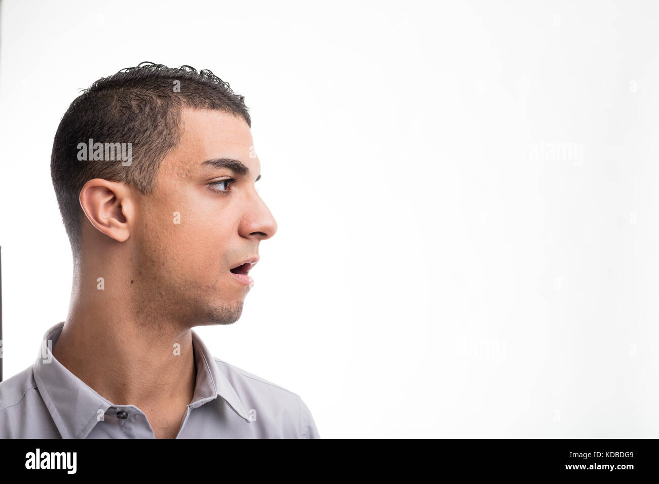 Lato headshot del giovane uomo guardando dritto contro uno sfondo bianco Foto Stock