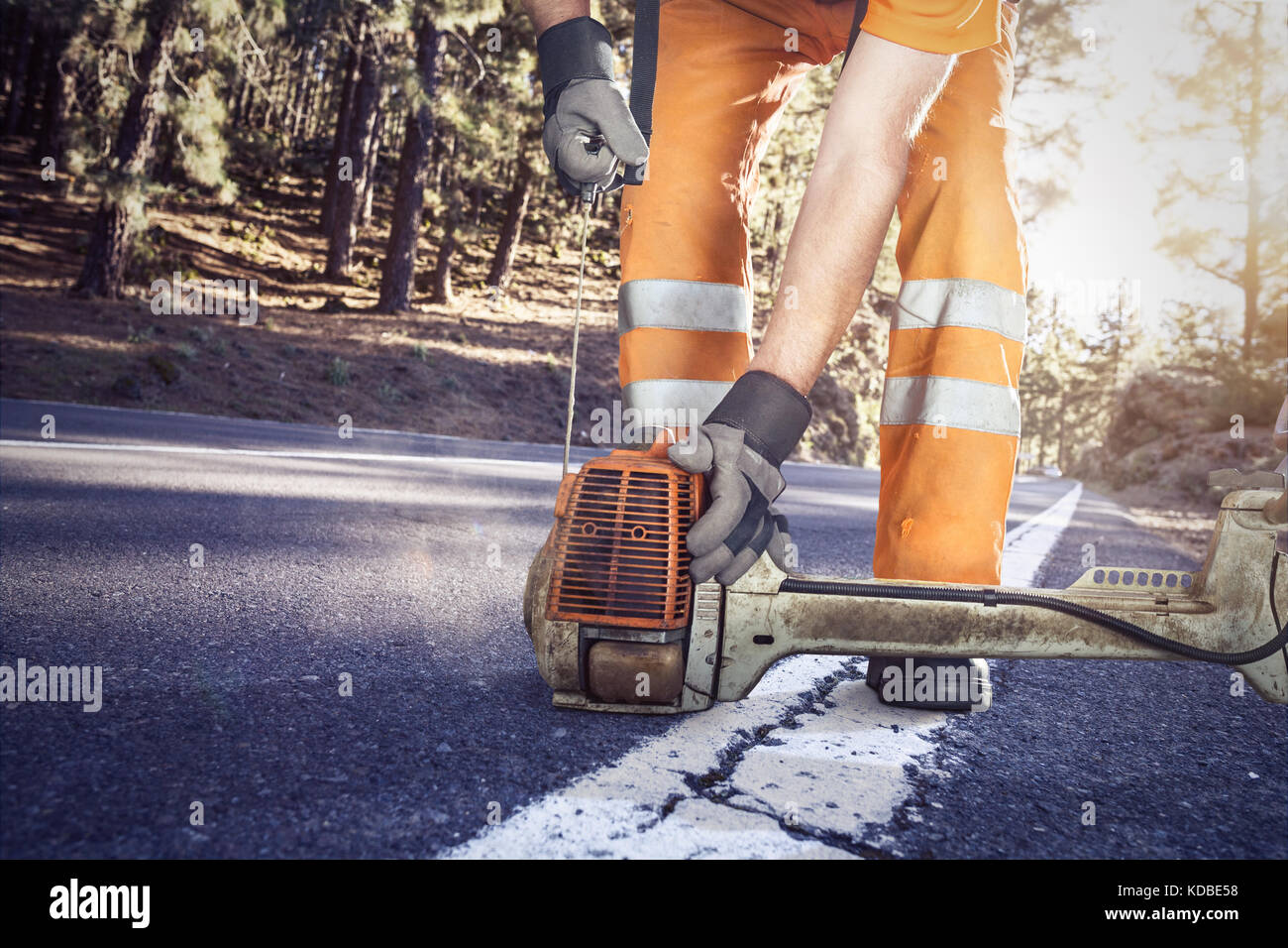 Lavoratore di strada a partire una brushcutter Foto Stock