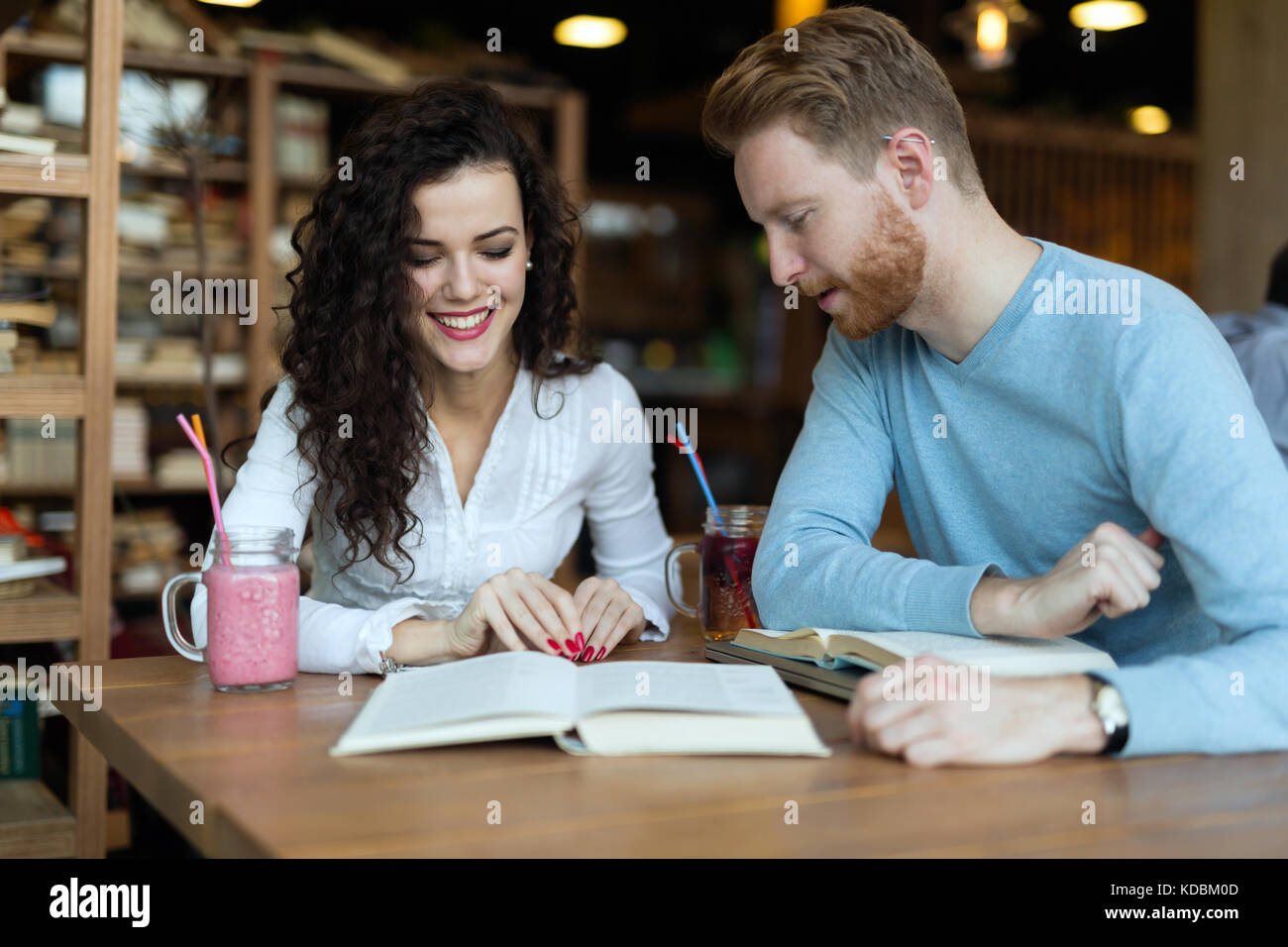 I giovani studenti di trascorrere del tempo in un coffee shop libri di lettura Foto Stock