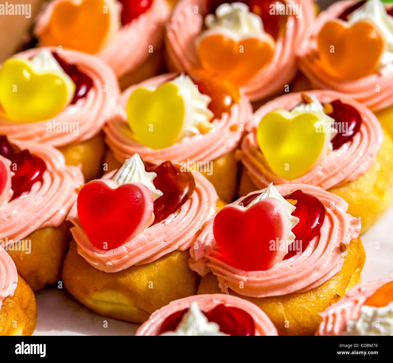 Ciambelle ripiene di panna montata e ricoperte di gelatina a forma di cuore e marmellata Foto Stock