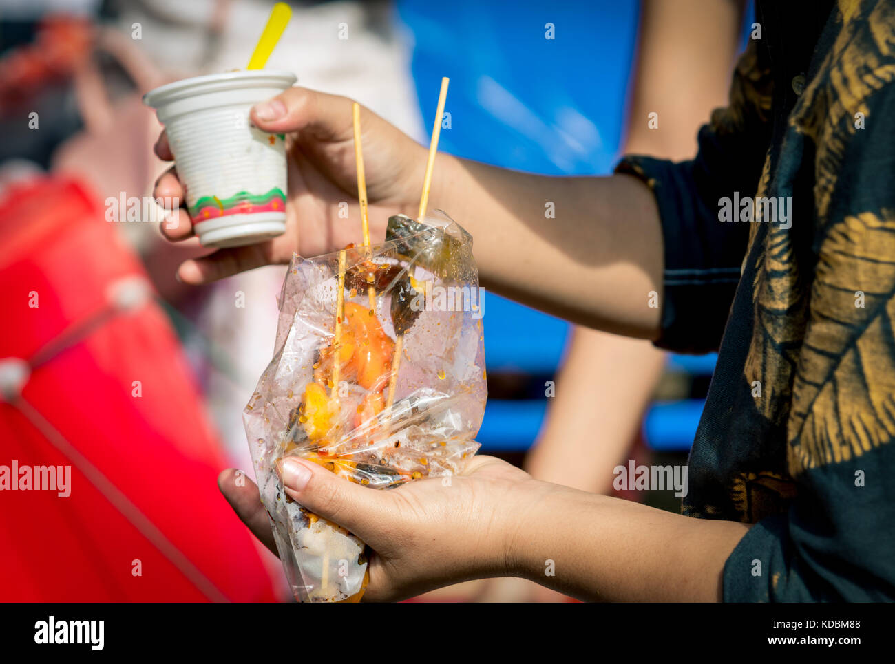 Le donne stanno mangiando calamari arrosto con salsa di frutti di mare nel sacchetto di plastica trasparente lungo con gelato in una tazza di plastica Foto Stock