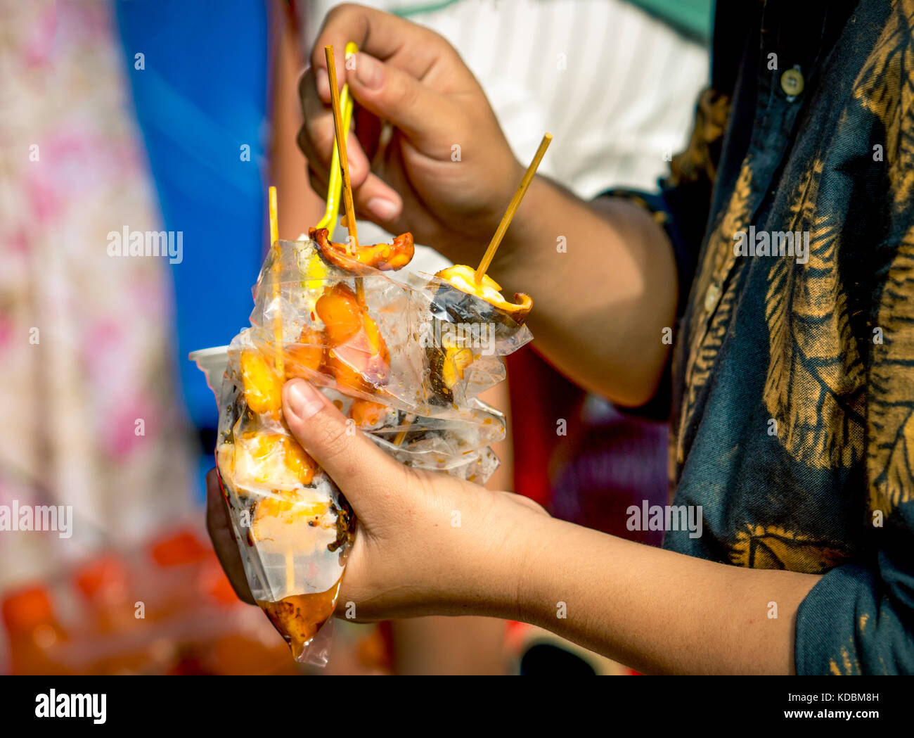 Le donne stanno mangiando calamari arrosto con salsa di frutti di mare nel sacchetto di plastica trasparente lungo con gelato in una tazza di plastica Foto Stock