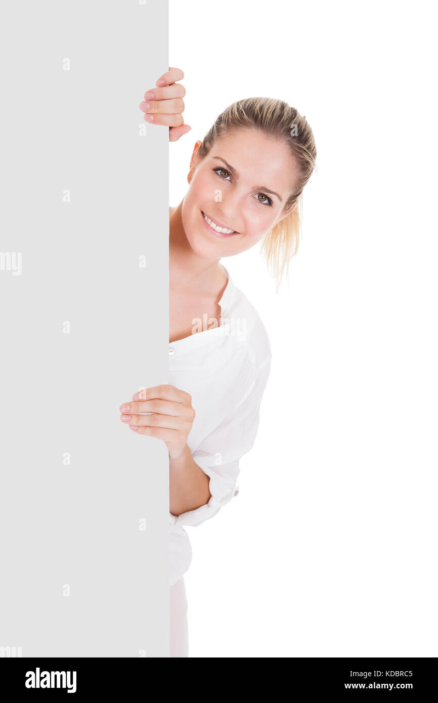 Giovane donna in piedi vicino alla targhetta vuota e presentante su sfondo bianco Foto Stock