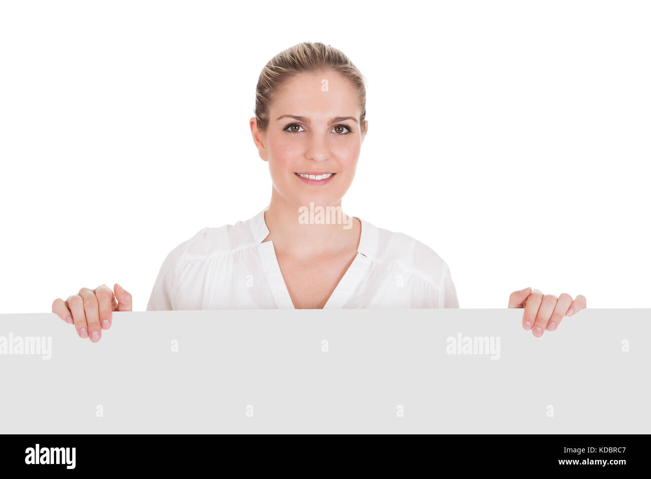 Giovane donna in piedi vicino alla targhetta vuota e presentante su sfondo bianco Foto Stock