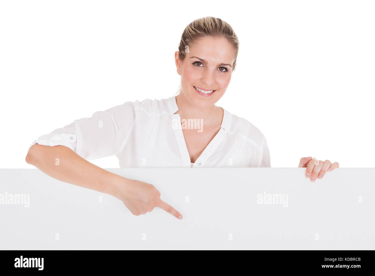 Giovane donna in piedi vicino alla targhetta vuota e presentante su sfondo bianco Foto Stock