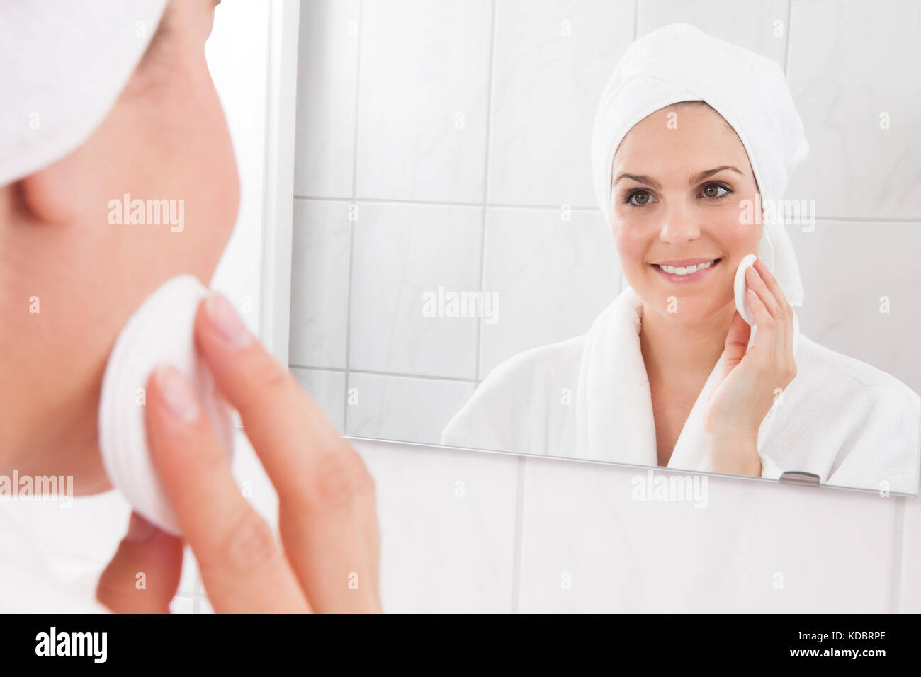 Giovane donna faccia di strofinamento con un tampone di cotone Foto Stock