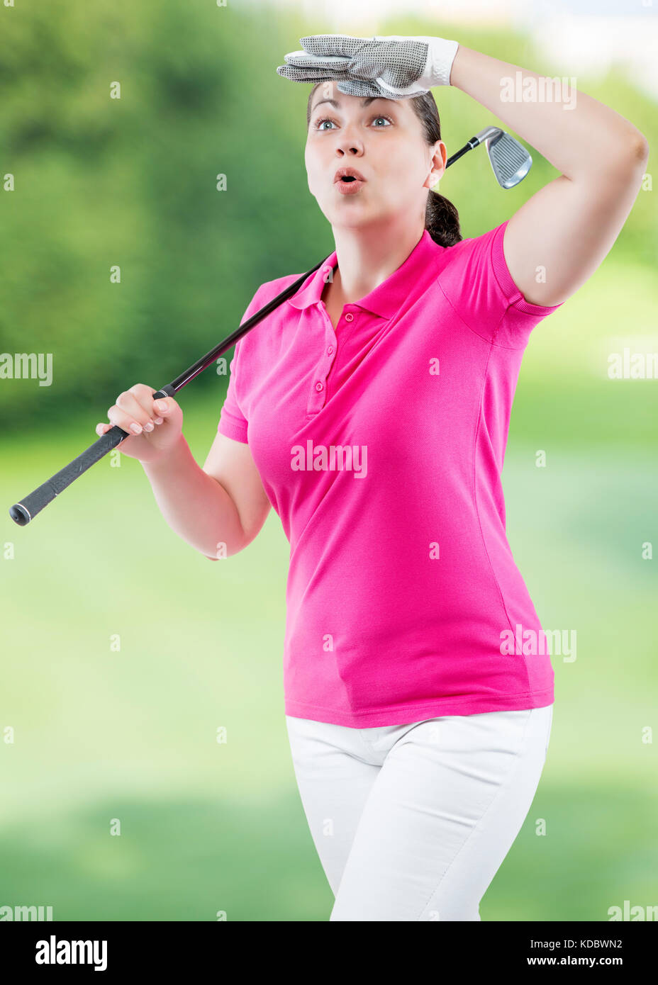 Atleta donna guardare la pallina la traiettoria di volo di golf su uno sfondo di campi da golf Foto Stock