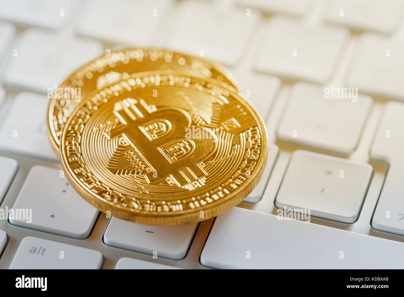 Monete d oro di cryptocurrency bitcoin su una tastiera bianca Foto Stock