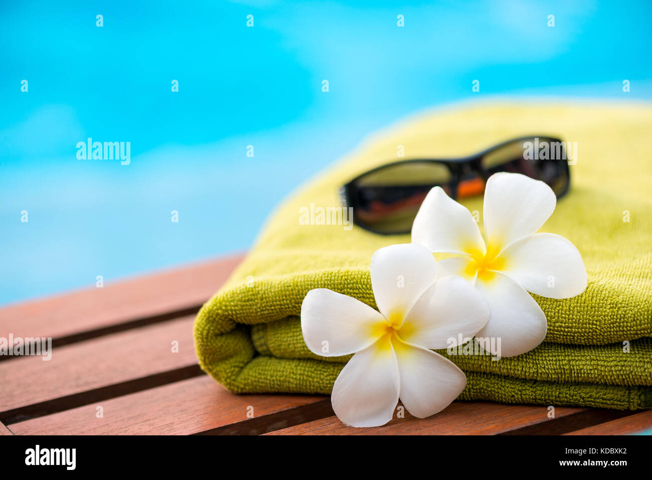 Bella plumeria fiori e un asciugamano di spugna in un lettino vicino alla piscina Foto Stock