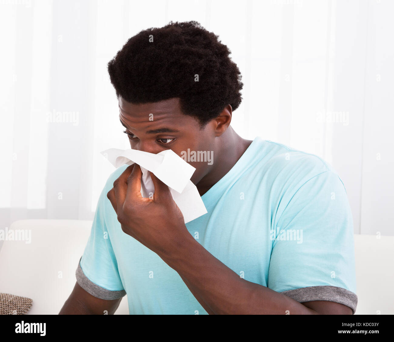 African giovane uomo avente un freddo il trattenimento del tessuto e soffiare il naso Foto Stock
