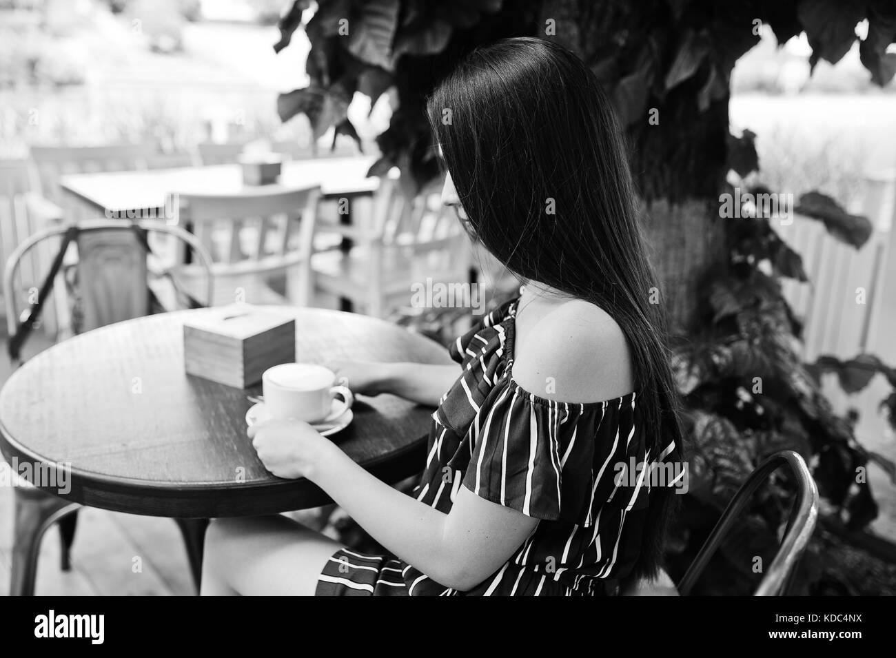 Gorgeous Brunette ragazza seduta sul tavolo in cafe con la tazza di caffè. Foto Stock