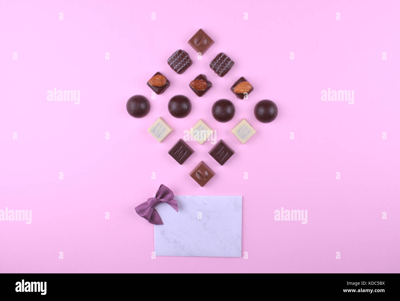 Raccolta di deliziose praline di cioccolato sulla tendenza rosa sfondo. Piatto stile laici. luogo per il vostro testo. Foto Stock