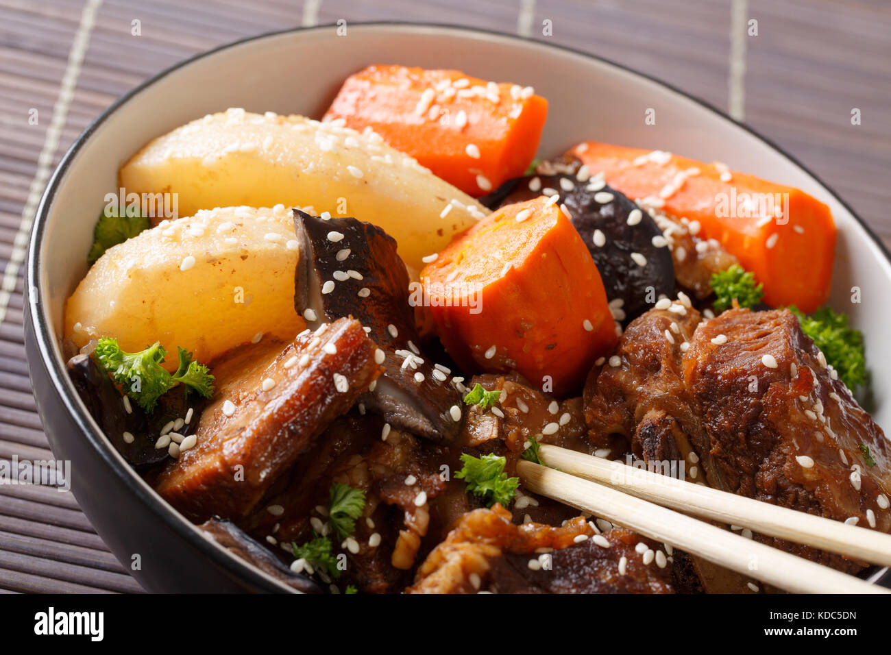 Cucina coreana: nervature stufati con funghi, pere e carote close-up in una ciotola. orizzontale Foto Stock