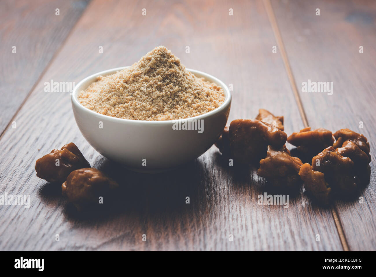 Asafoetida torta e polvere o hing o heeng che è un ingrediente importante in cucina indiana ricette con un grande cucchiaio di legno e di mortaio, il fuoco selettivo Foto Stock