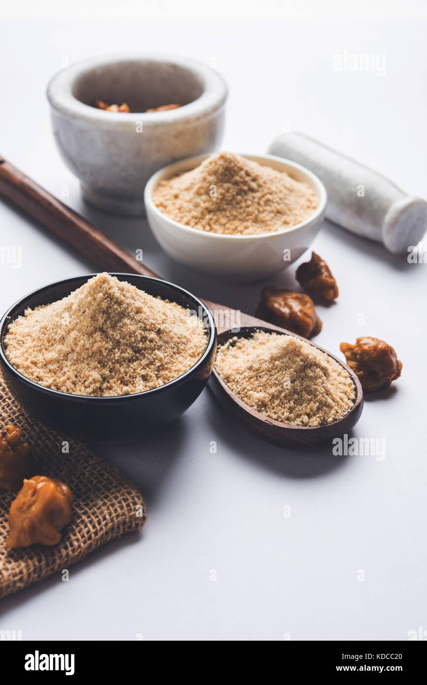 Asafoetida torta e polvere o hing o heeng che è un ingrediente importante in cucina indiana ricette con un grande cucchiaio di legno e di mortaio, il fuoco selettivo Foto Stock