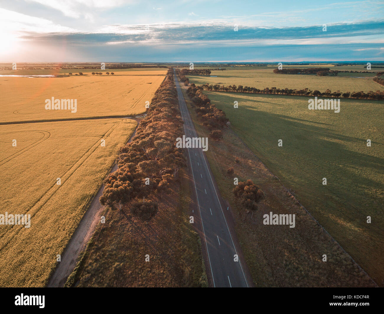 Vista aerea della strada rurale passando attraverso i terreni agricoli in campagna australiana al tramonto Foto Stock