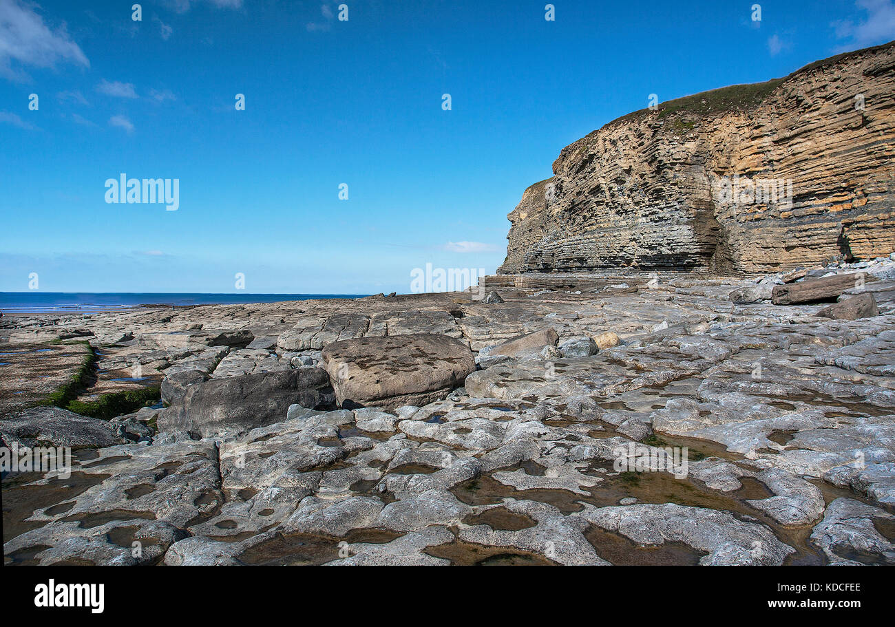 Un luminoso cielo blu sopra la pavimentazione di pietra calcarea e le scogliere del Dunraven bay, Glamorgan, Galles del Sud Foto Stock