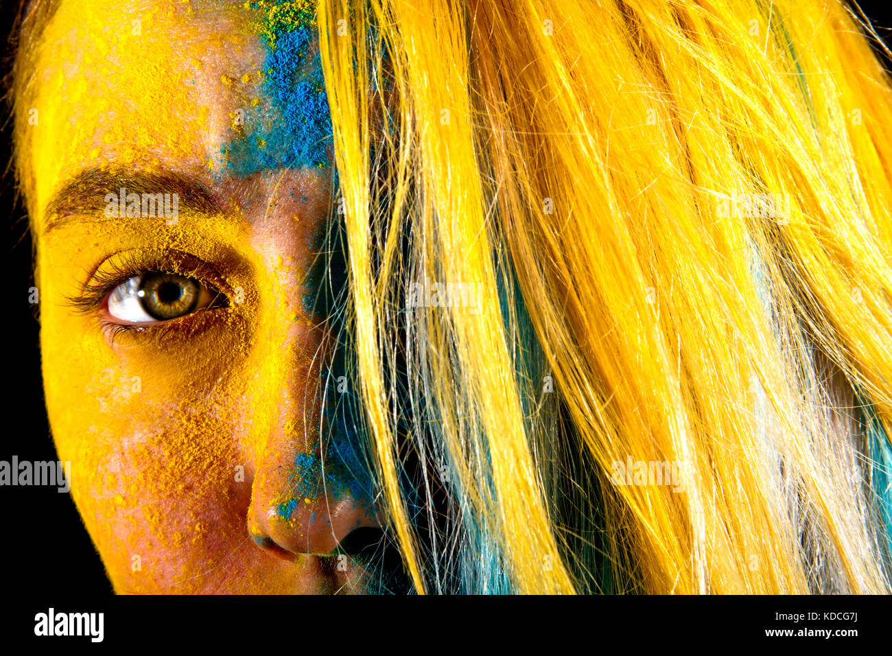Bella giovane donna coperta con i colori giallo e blu vernici Foto Stock