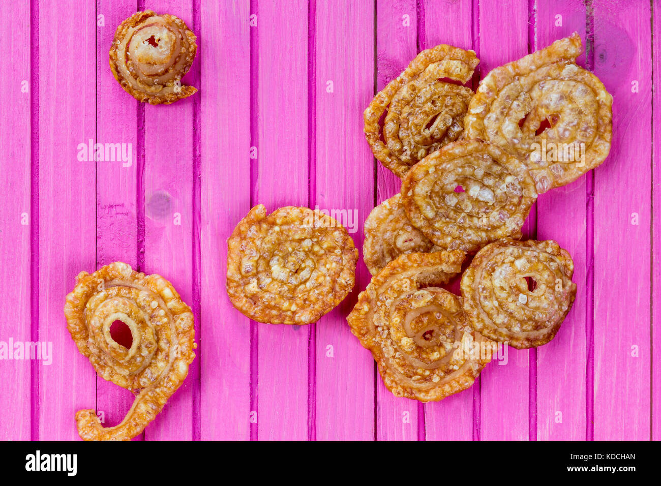 La carne di maiale cotta scoppiettante snack salato su una rosa di sfondo di legno Foto Stock