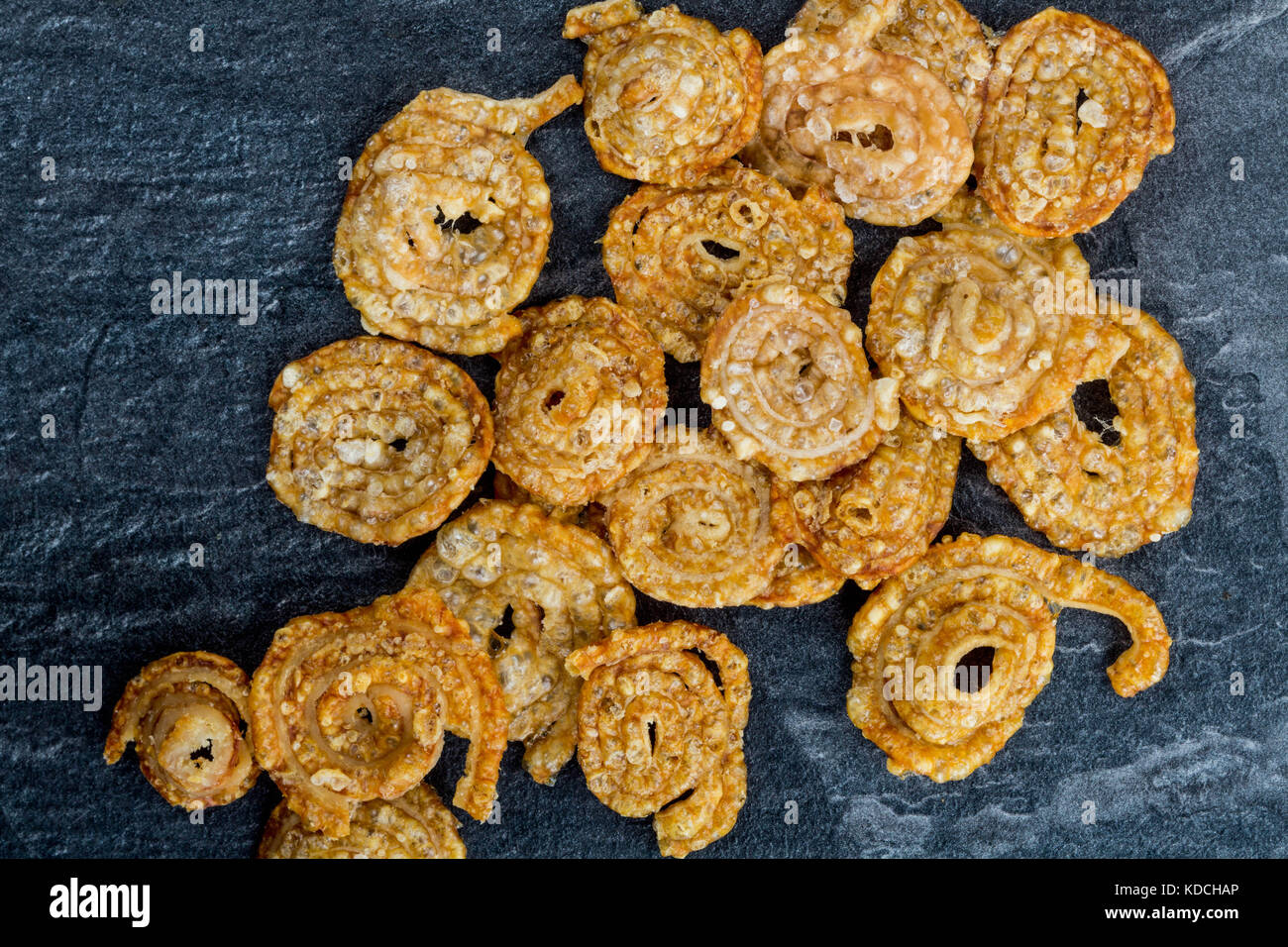 La carne di maiale cotta scoppiettante snack salato su un nero ardesia piastrella da cucina Foto Stock