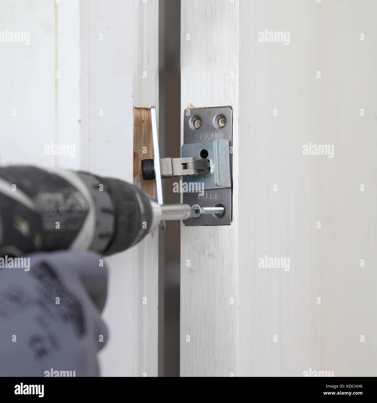 Un uomo di lavoro installa un nascosto più vicino ad una nuova porta tagliafuoco come parte della ristrutturazione di un blocco residenziale a Londra, Regno Unito. Foto Stock