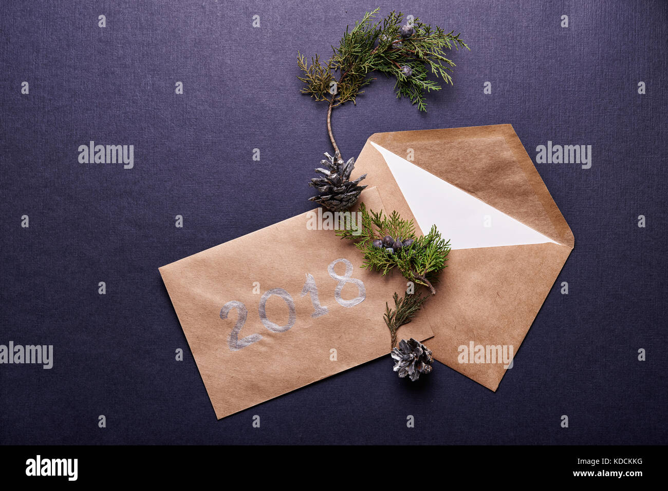Decorazione per il natale. browm busta, 2018 segno, evergreen ramoscello e cono di pino verniciato in argento su sfondo blu Foto Stock