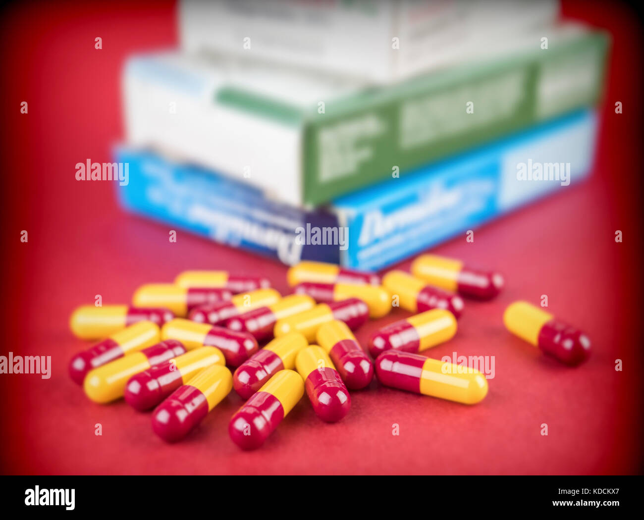 Alcune capsule di rosso e di giallo, scatole di medicinali Foto Stock